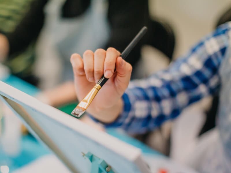 A person holding a brush at a painting class.